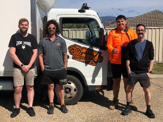 Ontime Movers team members standing in front of a branded white moving truck in a residential Canberra neighborhood, showcasing professionalism, team spirit, and readiness for local or interstate relocations.